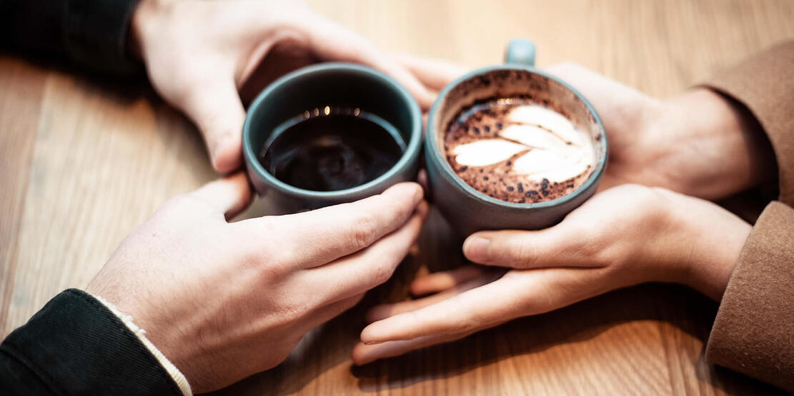 Two people talking over coffee to share tips for a stress-free holiday season.
