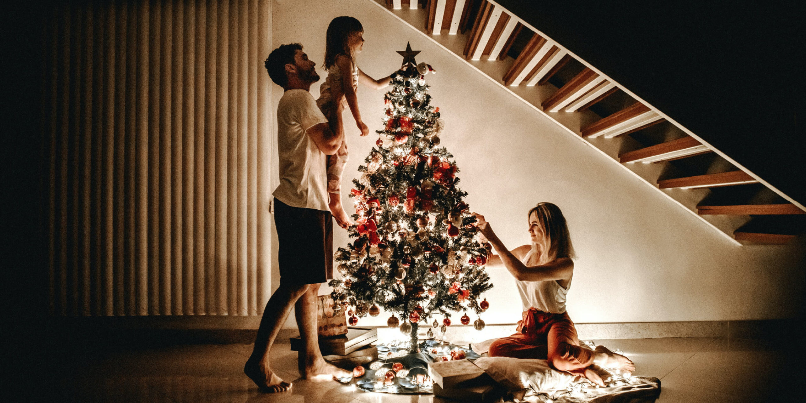 Parents and child having a stress-free holiday at home atound a Christmas tree.